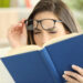 Woman suffering eyestrain trying to read a book at home